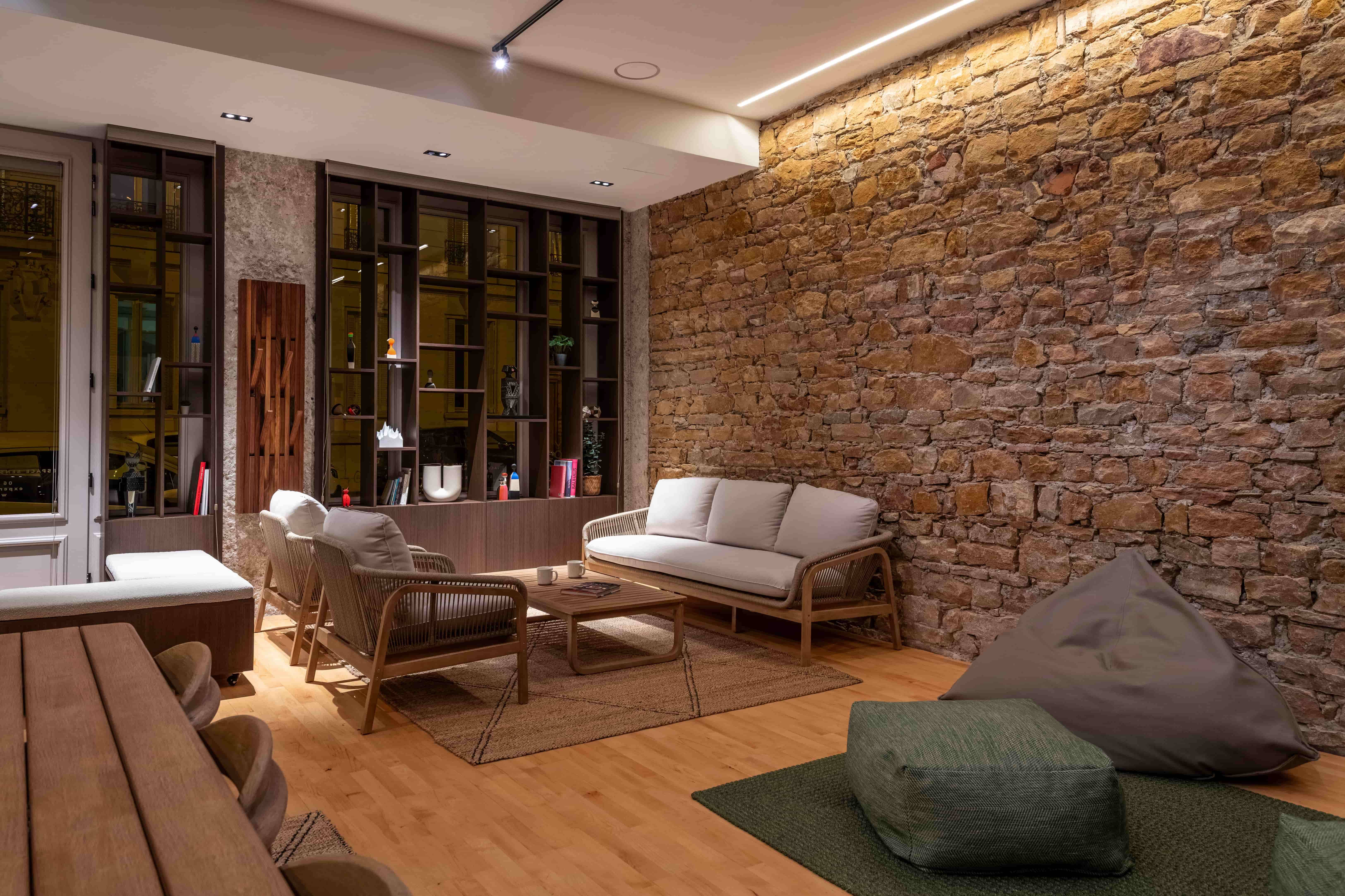 Studio Yoku avec mur en pierres, canapé et poufs 